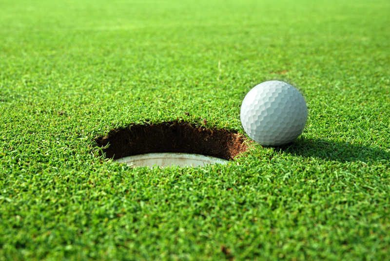 草坪上在球洞旁的高尔夫球