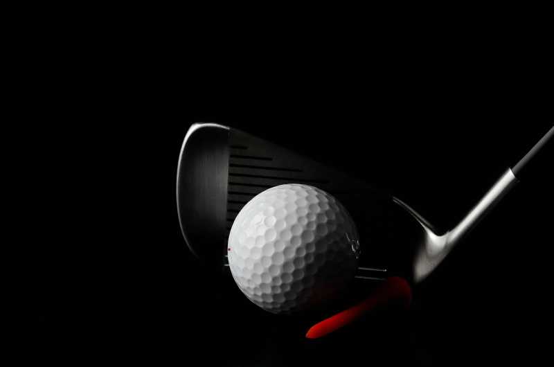 黑暗中的接触的球杆和高尔夫球