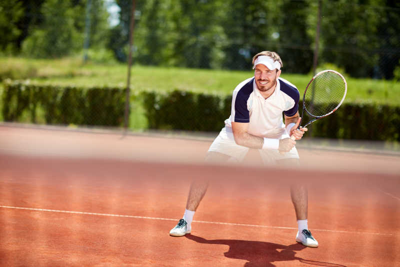 男子网球运动员在网球场上拍球拍
