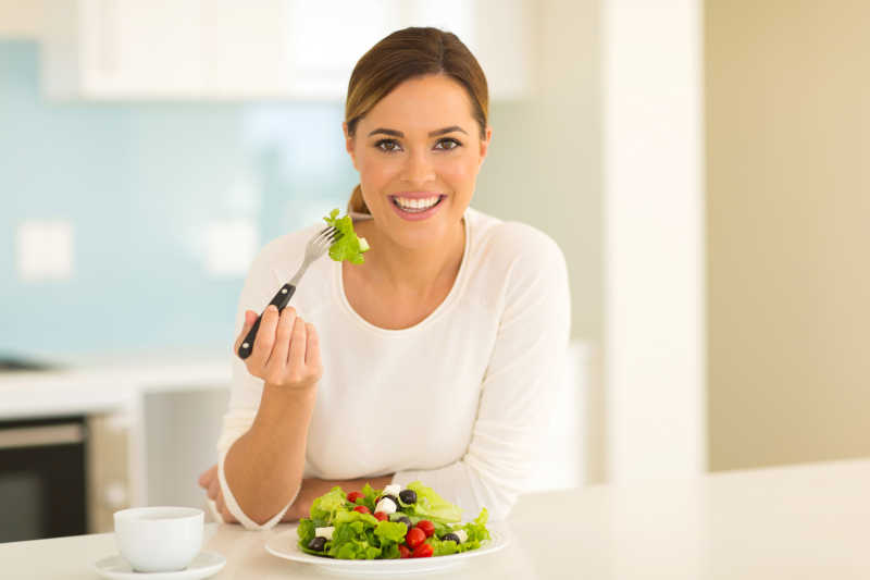 健康年轻女性在家吃绿色沙拉