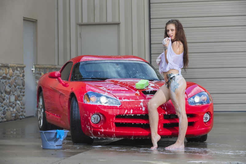 性感的金发女郎在洗红色的跑车
