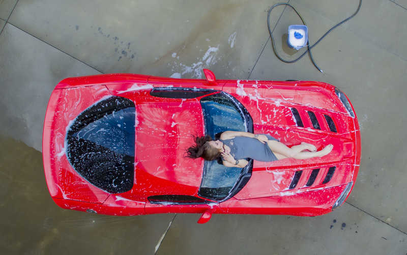 性感的洗车女郎躺在红色跑车上