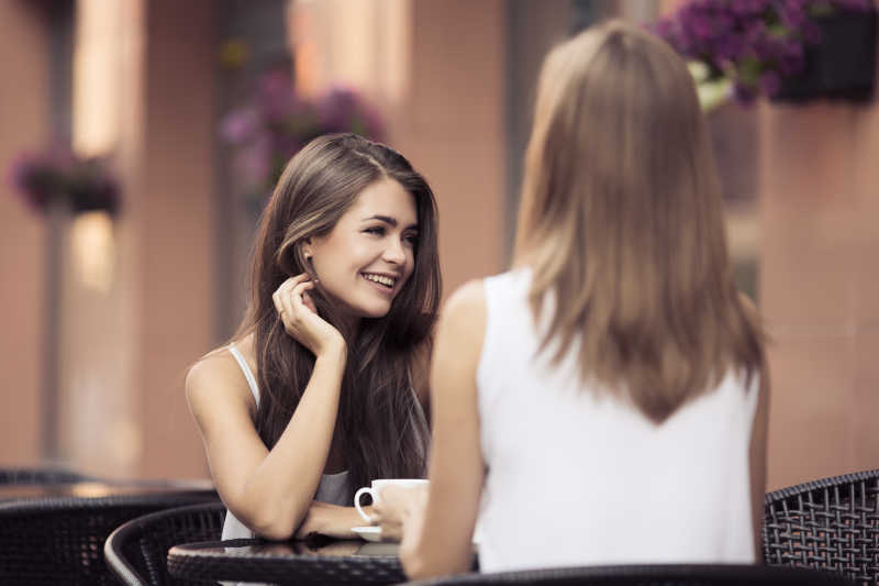 在户外咖啡馆互相交谈的年轻女人