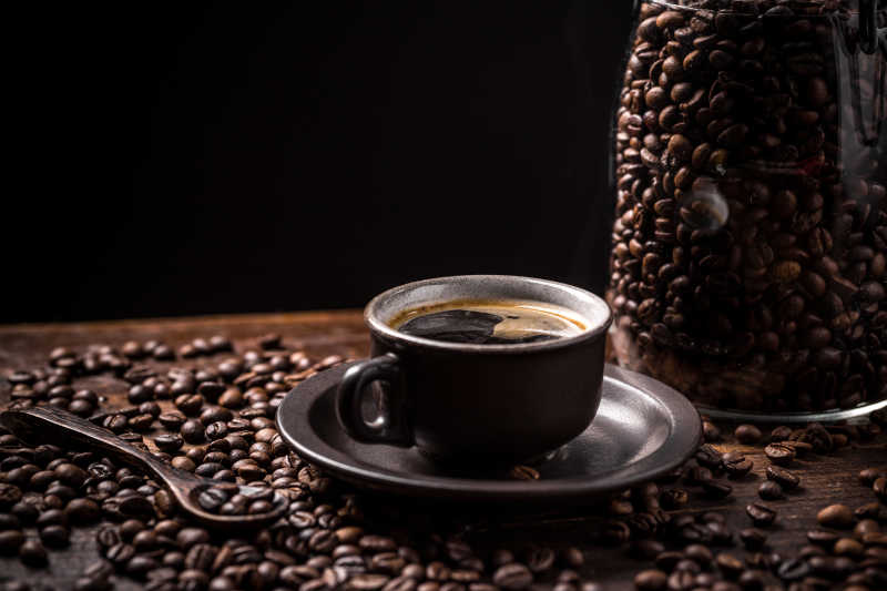 黑色背景下木桌上的咖啡豆和一杯制成的咖啡