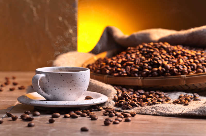 木桌上的棕色咖啡豆和白的咖啡杯里的咖啡早餐
