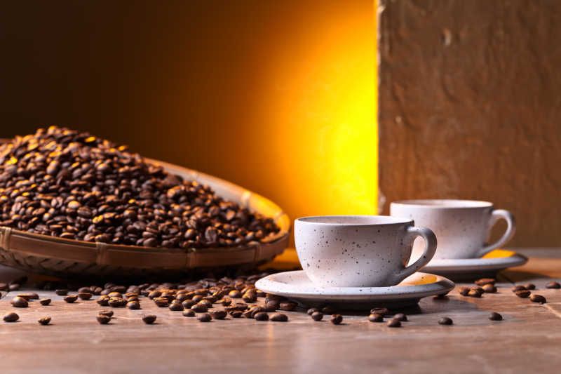 早晨木桌上的咖啡豆和白色咖啡杯里的咖啡早餐