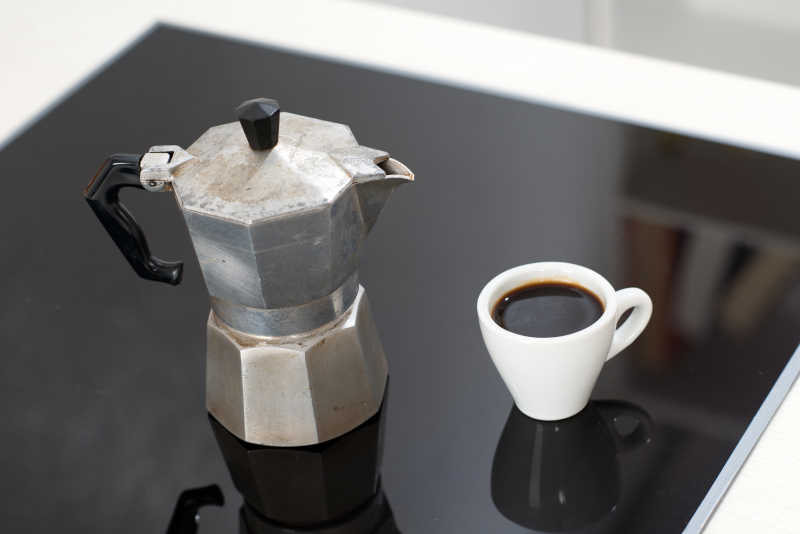 黑色玻璃桌上的意大利浓咖啡和咖啡壶