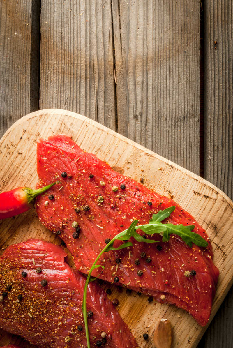 木桌上盘子里的调好的红色生肉