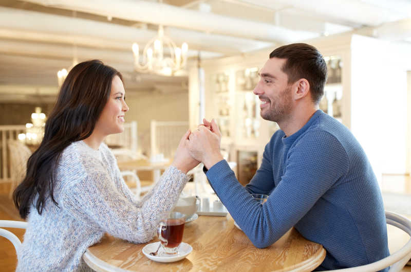 幸福的夫妇喝茶时手拉手