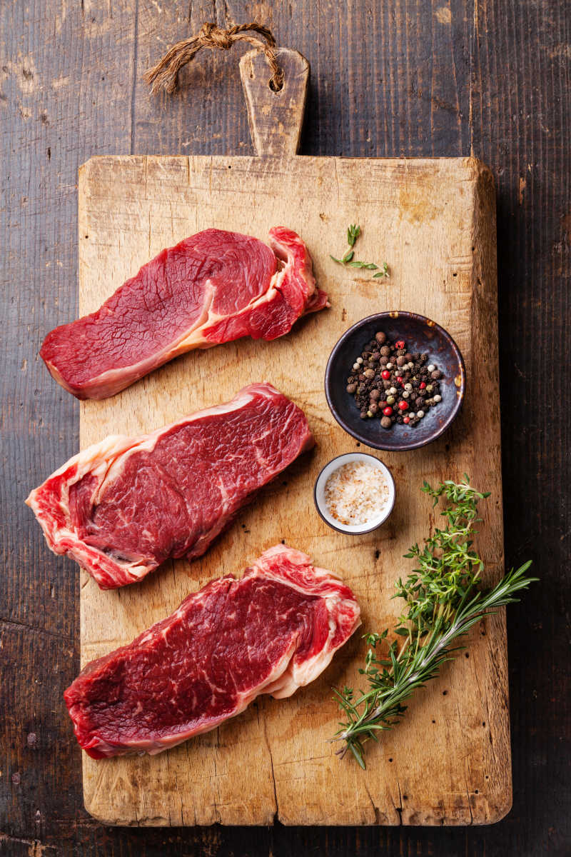 生肉肉糜牛排在黑木制背景下调味和调味