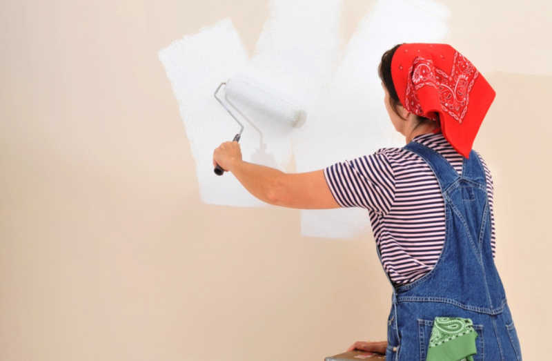 在墙壁上刷油漆的女人