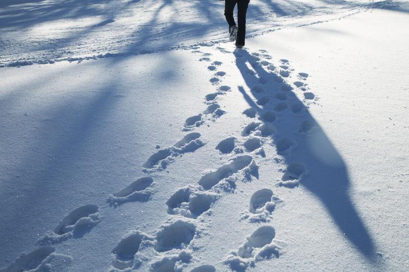 阳光鞋印与人影行走在清新的雪景中