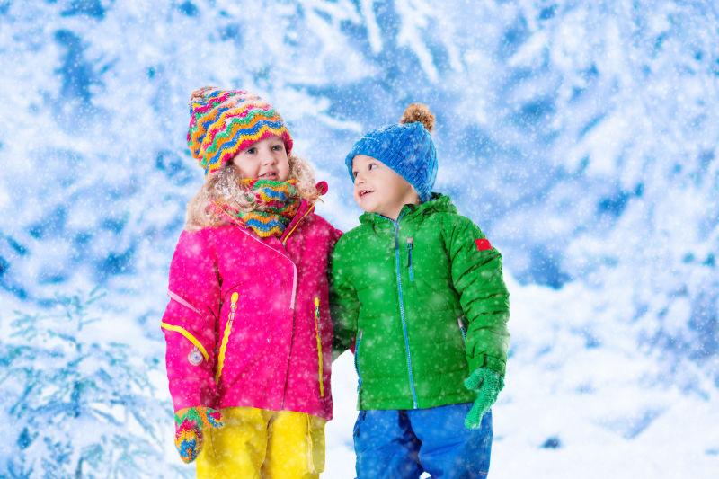 戴着彩色帽子的小女孩和小男孩正在捉雪花