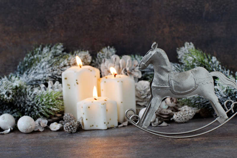 木桌上圣诞装饰旁的白色蜡烛