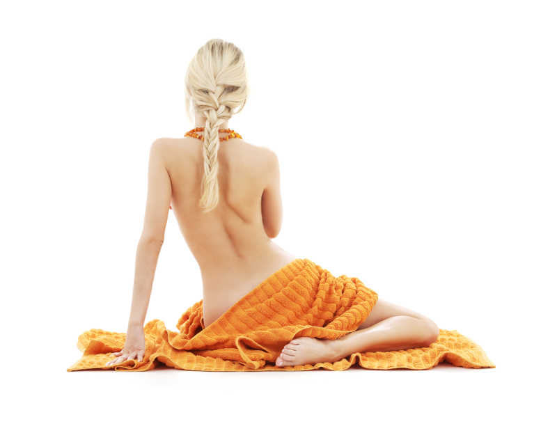 漂亮性感的年轻女人坐在橙色毛巾上