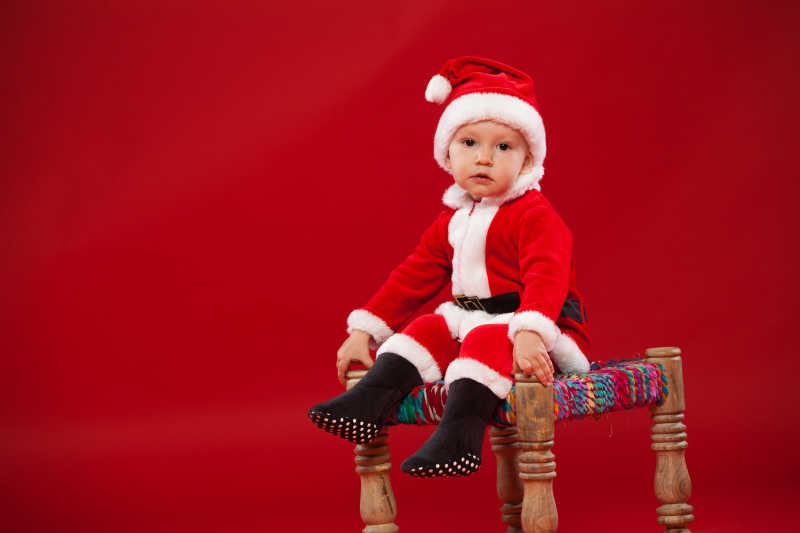 坐在椅子上的穿着圣诞老人衣服的孩子