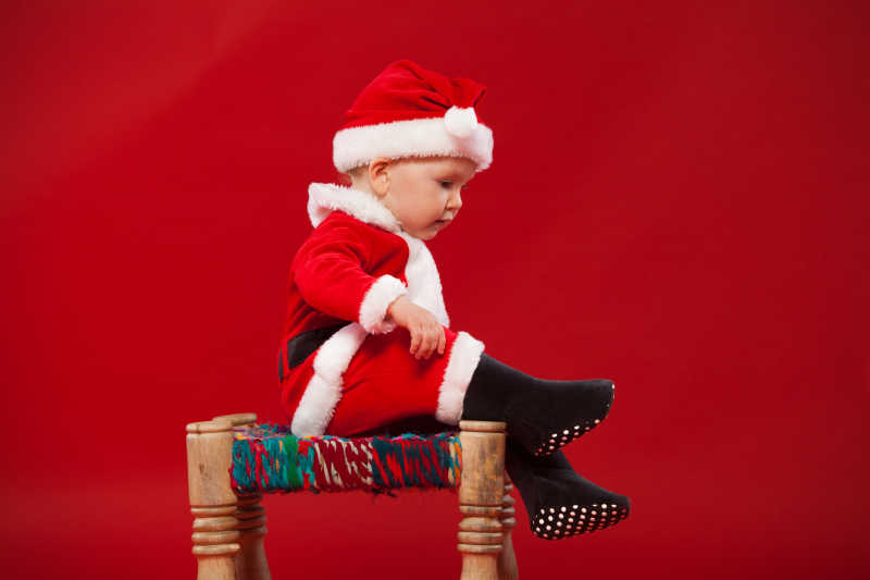 坐在椅子上的穿着圣诞衣服可爱的孩子