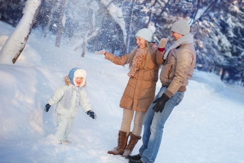 带着孩子在雪地里玩雪的一家人