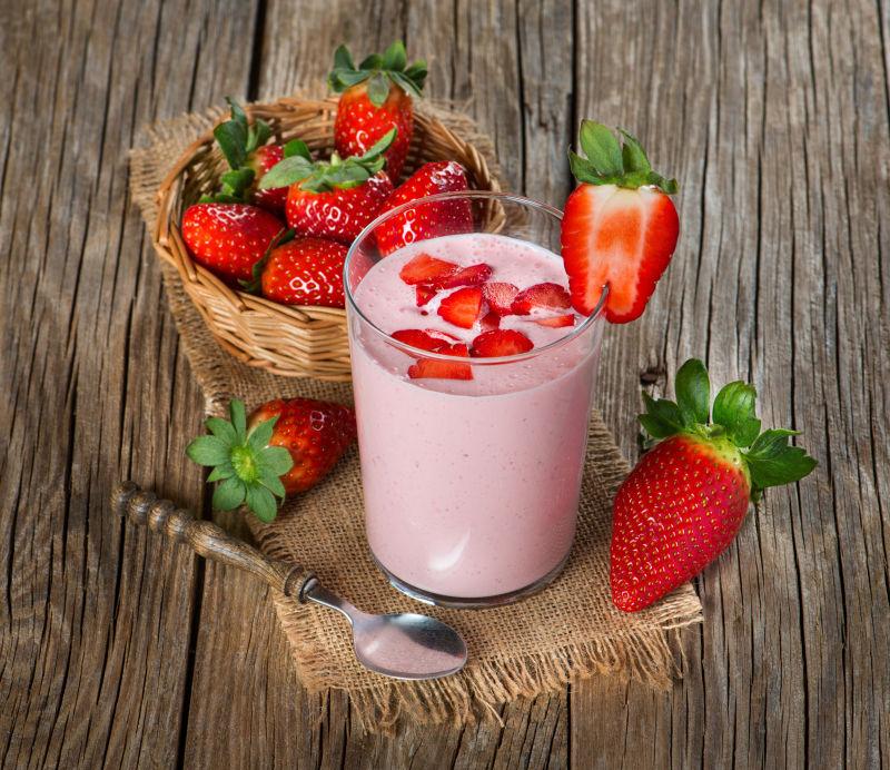 木桌上的新鲜草莓奶昔和新鲜的草莓