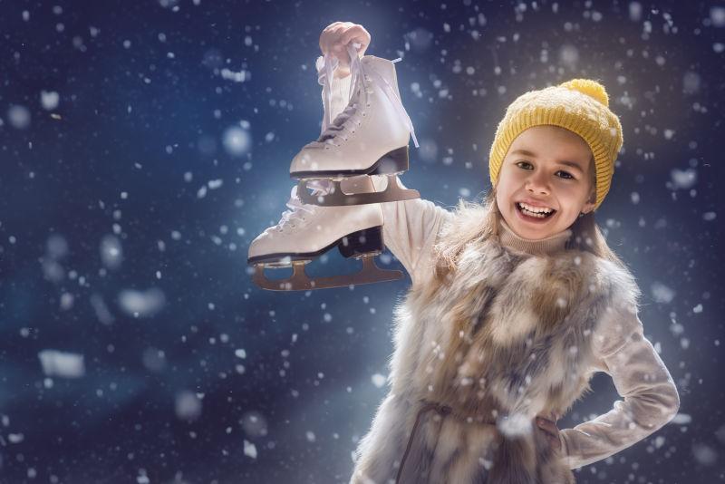 雪天手里拿着溜冰鞋的小女孩