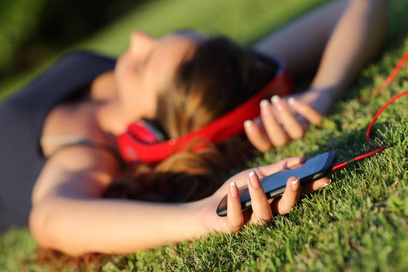 躺在草地上用手机听音乐的女孩
