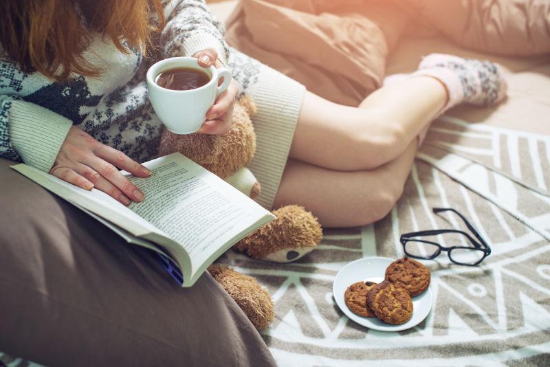 端着咖啡在床上看书的女孩