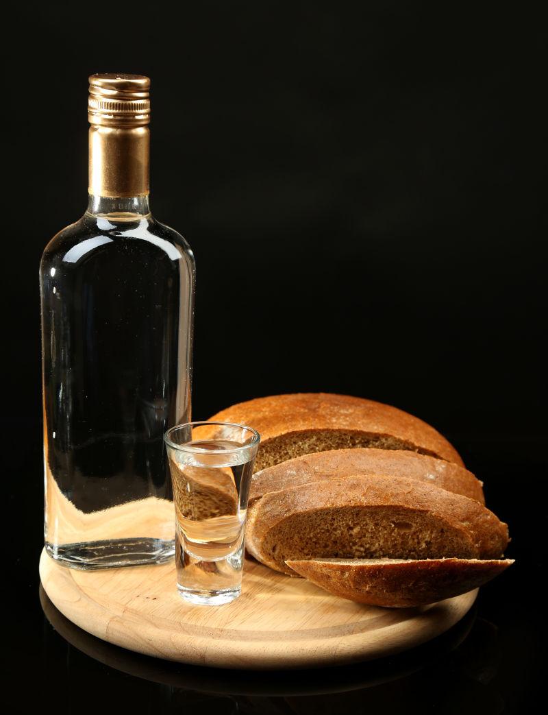 一瓶伏特加新鲜面包和玻璃在木板上