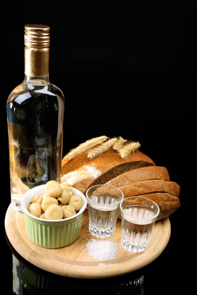 伏特加酒腌制的蘑菇与新鲜的面包玻璃杯在黑色背景下