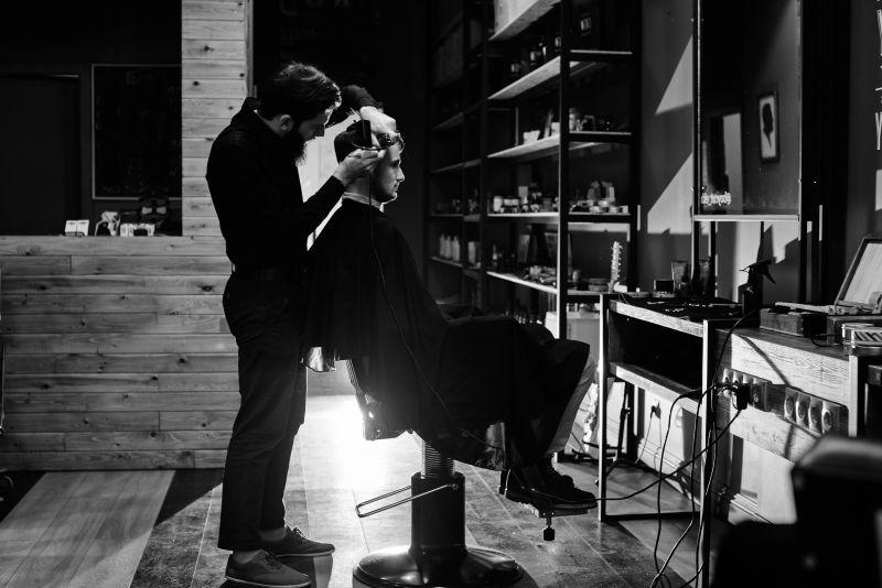 黑色背景下正在理发的发型师与顾客