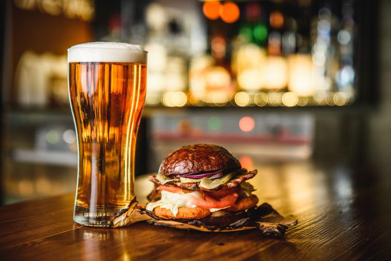 酒吧木桌上美味的汉堡包和啤酒