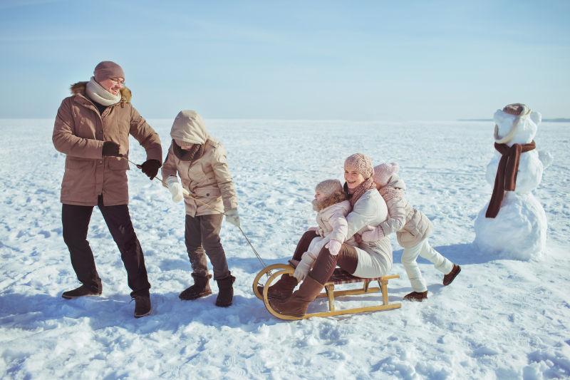 冬天雪地里玩雪橇的一家人