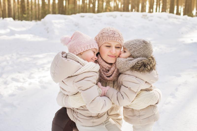 雪地里两个小女孩依偎在妈妈的怀里