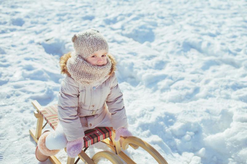 冬季雪地里的小女孩坐在雪橇上