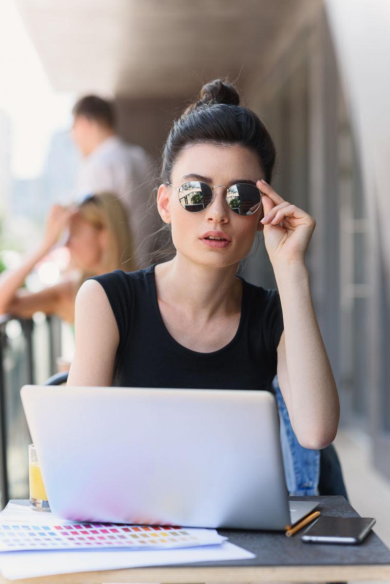 戴着墨镜使用笔记本电脑办公的女人