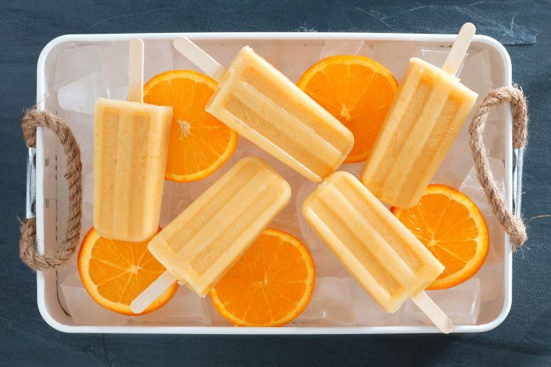 白色冰盘里的自制甜橙冰棒和切片橙子
