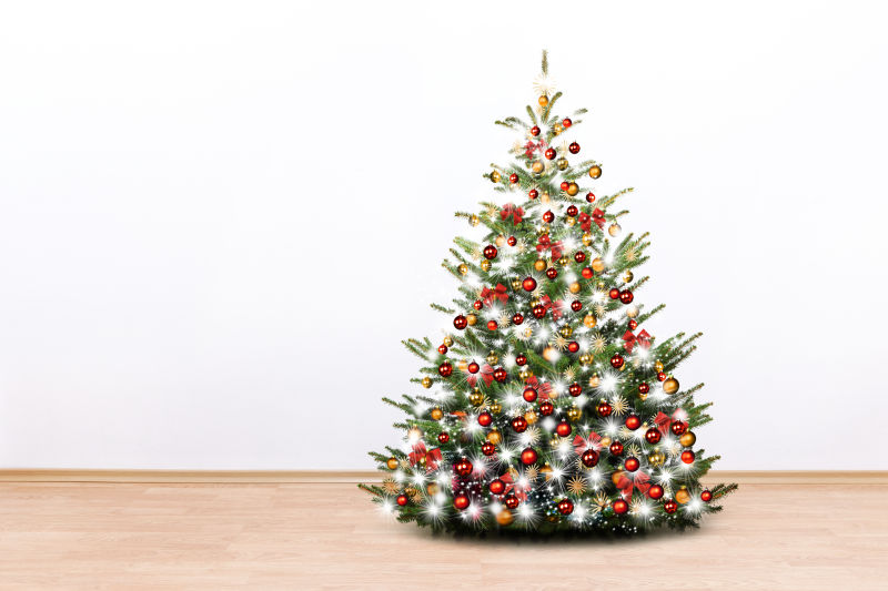 白色墙边的一棵挂着各种装饰球的圣诞树
