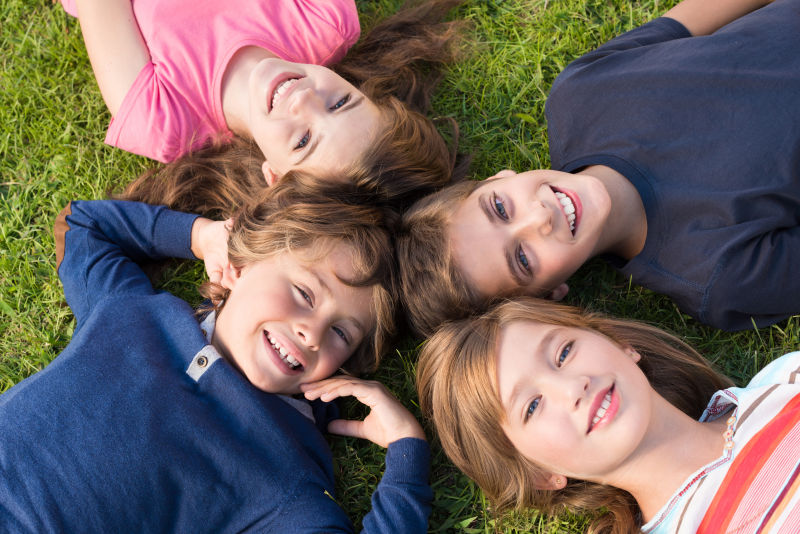 四个躺在草地上微笑的小学生