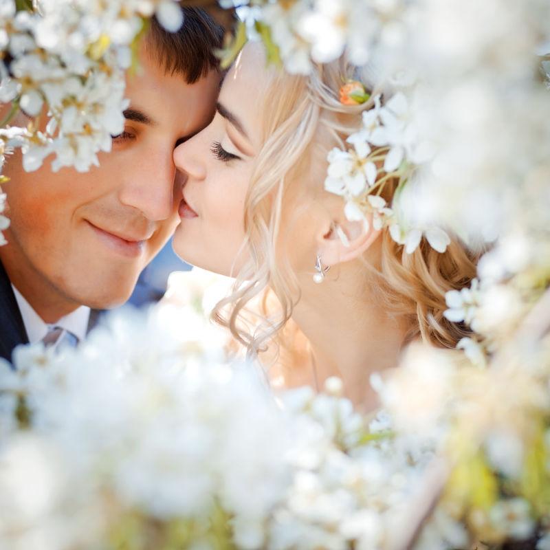 美丽的花朵旁接吻的新婚情侣