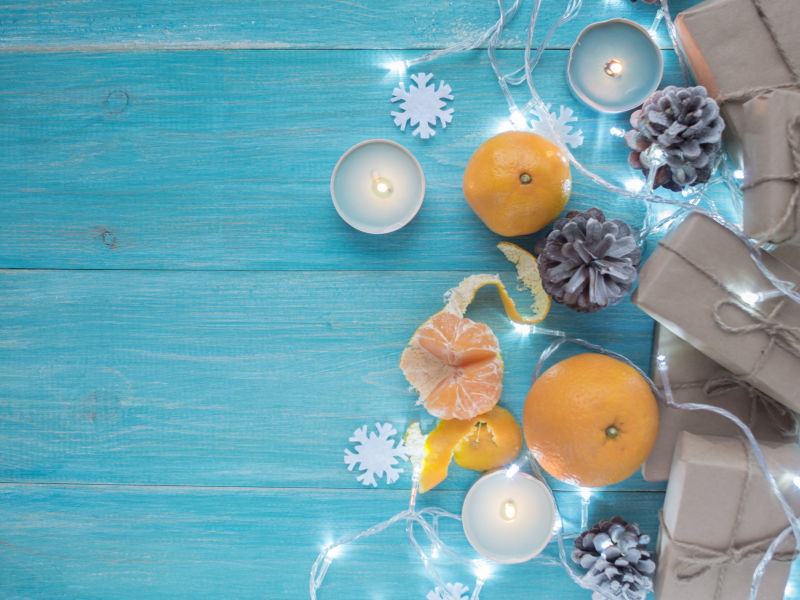 蓝色木板上的牛皮纸礼盒和橘子以及圣诞装饰品