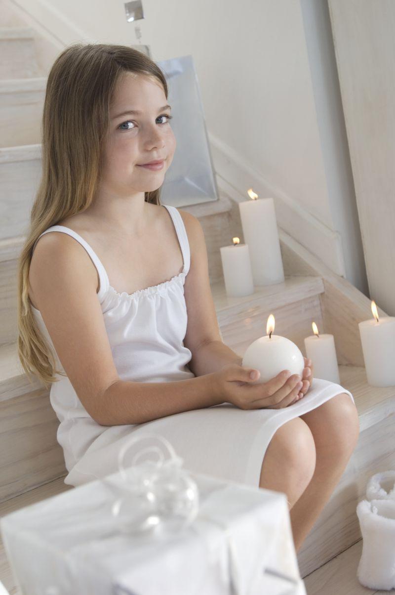 穿白色裙子坐在楼梯上捧着蜡烛的女孩