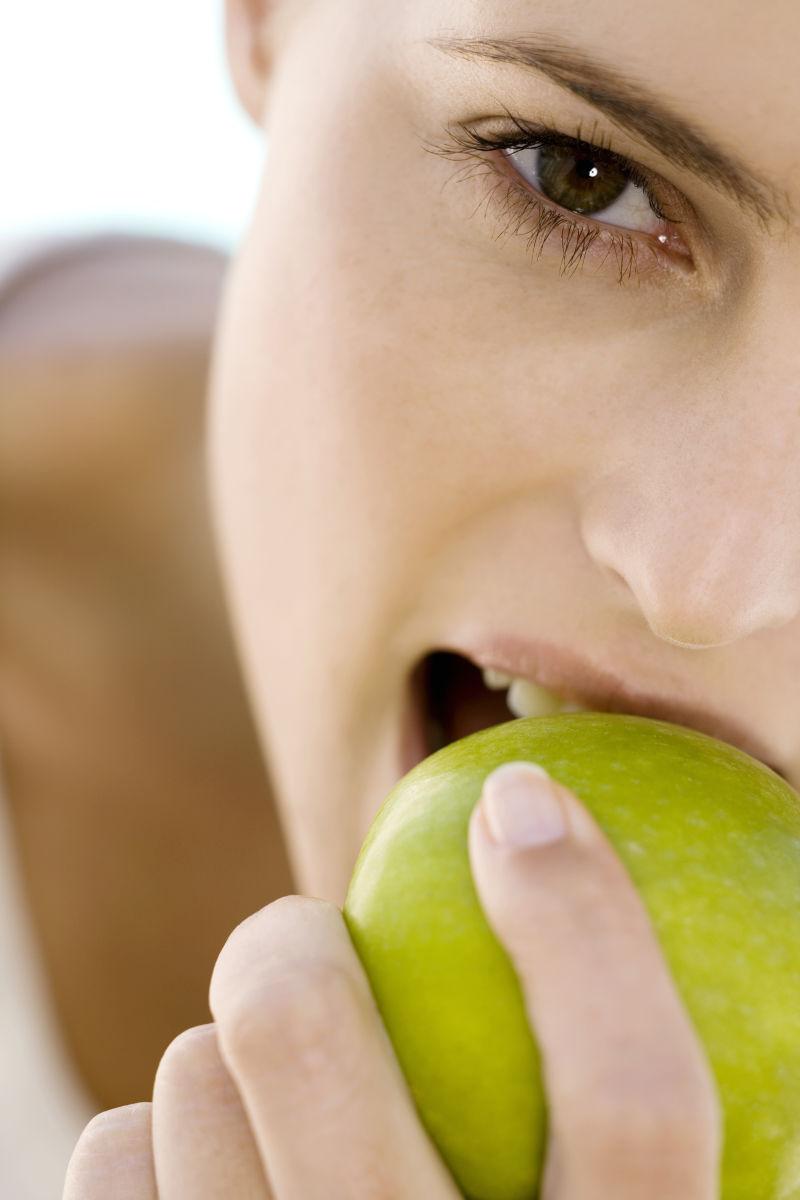 一个年轻女人在室内吃苹果