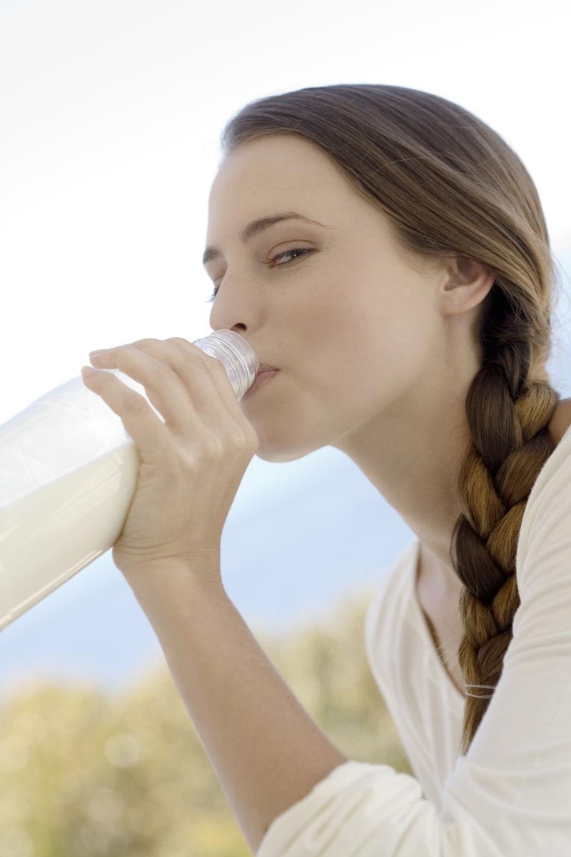 一个年轻的女子从瓶子里喝牛奶