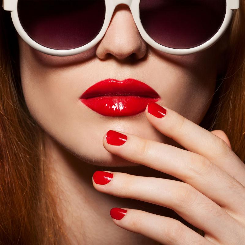 红色指甲和性感红嘴唇的带太阳镜的美女