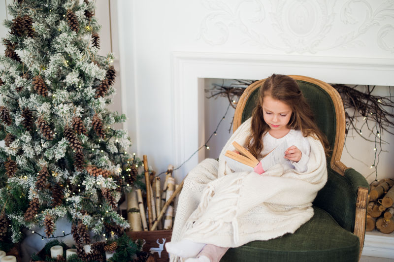 圣诞树旁边的小女孩在认真的读书