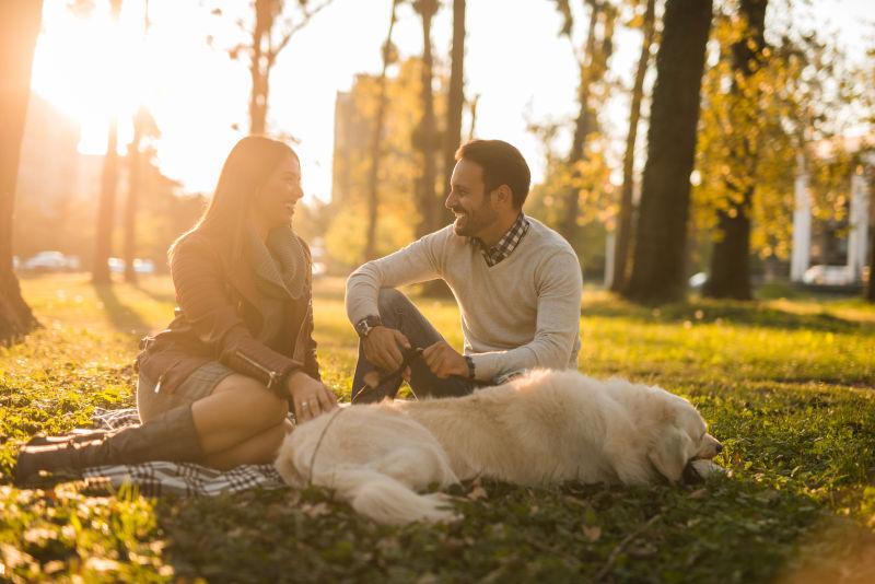 幸福的夫妻在公园和狗狗度过假日