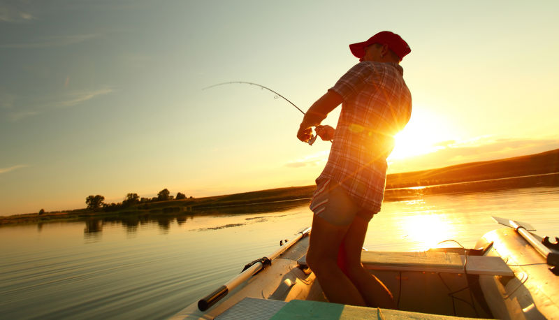 落日在小船上钓鱼的男人