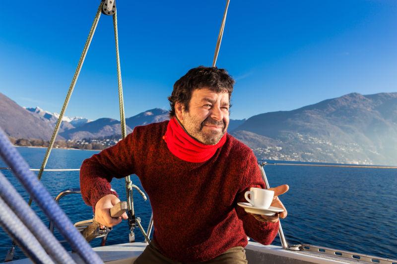 拿咖啡掌握船方向的男子