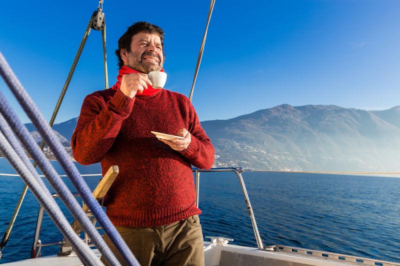 喝咖啡的男人在船上眺望远方