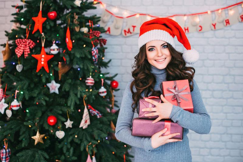 微笑的妇女在圣诞老人帽子与礼品盒