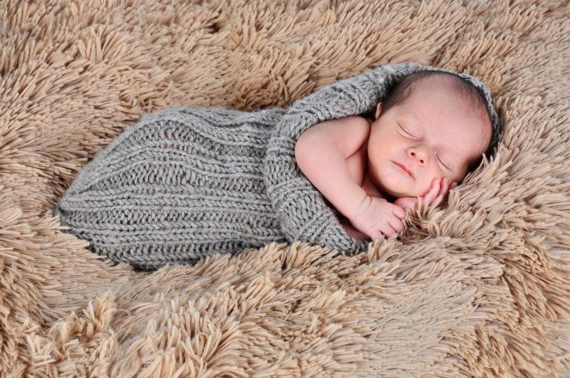 横卧在毛毯上熟睡的小婴儿